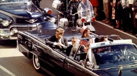 General view of the car carrying JFK and Jackie Kennedy, crowd of crowd