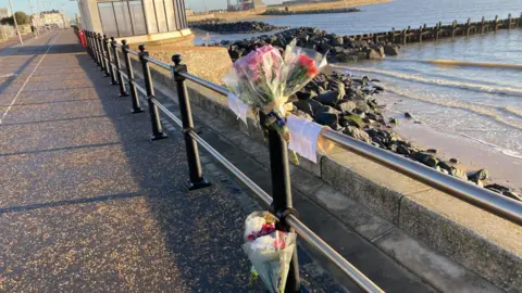 Luke Deal/BBC Flowers tied to railings at the scene