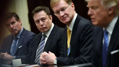 Getty Images Elon Musk, left center, and Wendell P. Weeks, right center, listen to President Donald Trump, right, as he meets with business leaders at the White House on Monday January 23, 2017 in Washington, DC.