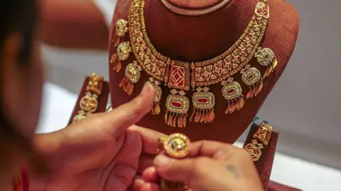 Getty Images A woman looks at a gold necklace and earrings at a jewellery store at Zaveri Bazaar during the festival of Dhanteras in Mumbai, on Tuesday