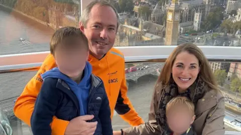 A man and a woman on a pod in the London Eye with their children, who have their faces blurred