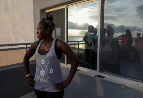 Zohra Bensemra / Reuters Khadjou Sambe stands on a patio and looks out to sea