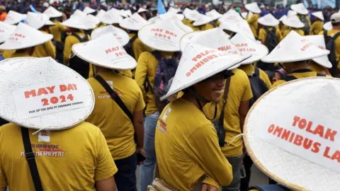 Reuters Labourers wearing yellow t-shirts and white conical sun hats attend a protest during a May Day rally in Jakarta, Indonesia.