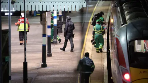 PA Media Black-clad police officers and emergency crews wearing green-and-yellow coveralls on the platform of Huntingdon train station, where a train has stopped