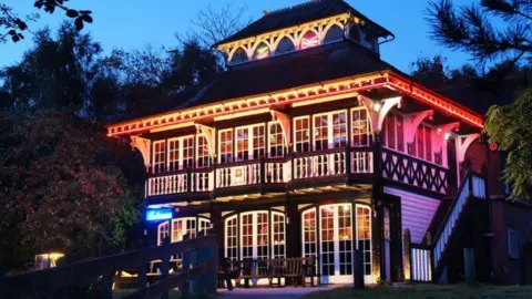 Zaks Diner A Victorian sports pavilion building is lit up at night with an orange glow