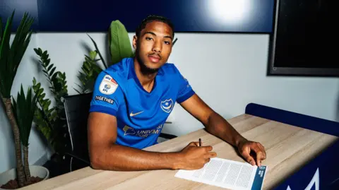 Benjamin Arthur signs his Portsmouth contract.