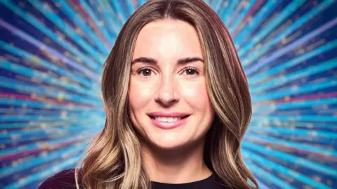 PA Media Dani Dyer with her light brown hair worn down. She is wearing a black top.