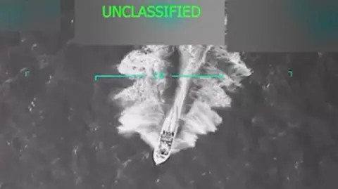 Donald Trump/Truth Social A grainy aerial video still shows a motor boat speeding across choppy waters