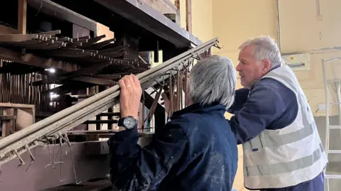 Two men grappling with intricate organ parts 