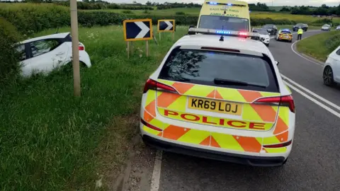 Leicestershire Police Police car dealing with scene after a car comes off the road at Pork Pie Way near Melton Mowbray