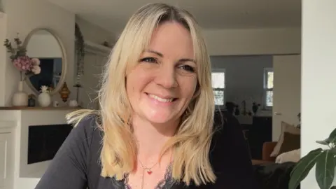 Chloe Fosse, a smiling blonde woman sitting in her home 