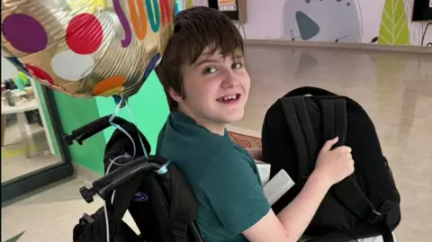 Provided A young girl in a wheelchair with a 'get well soon' balloon behind her .