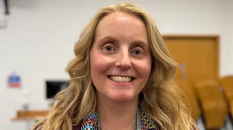 Naomi Tweddle, a blonde-haired woman, smiles at the camera.