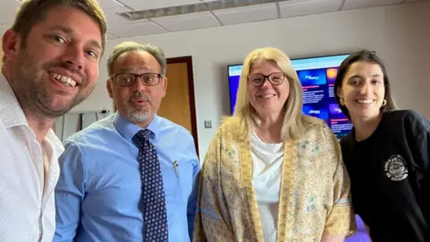 Jon Wright/BBC Jon Wright, Craig D'Chuna, Annie Clements and Nina Arya all smile for a selfie inside a BBC office