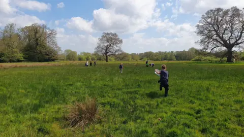 Julia Moore/BBC Children running on a large field. 