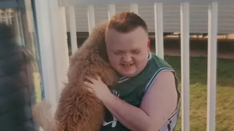 Ben Miller, 19, who has Smith-Magenis syndrome playing with a family dog on holiday.