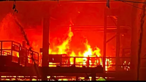 Colleen O'Leary Close up image showing a large fire burning tn the steelworks with large yellow flames. 