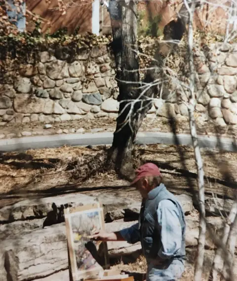 UGC A man wearing a red cap and blue shirt is seen painting in a landscape