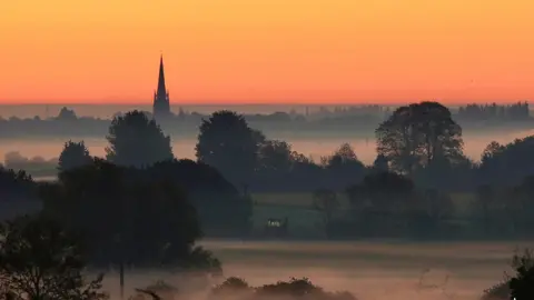 Martyn Hopkins An orange sunrise with mist and fog over the fields.