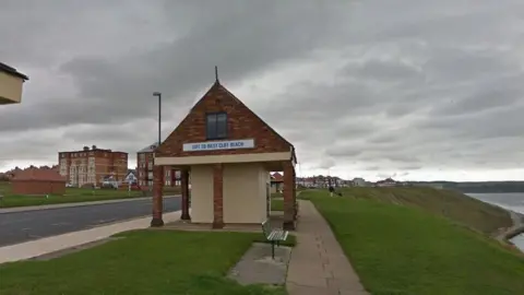 Building on coast with 'lift to west cliff beach' sign on it