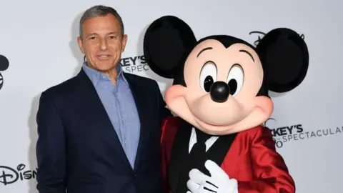 Getty Images Disney chief Bob Iger poses with Mickey Mouse in Los Angeles.