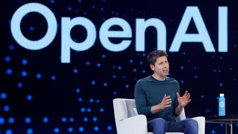 Getty Images Open AI CEO Sam Altman speaks during Snowflake Summit 2025 at Moscone Center on June 02, 2025 in San Francisco, California. He is seen sitting on a white arm chair, wearing a dark long-sleeved dark teal shirt and blue denim jeans, gesturing with his hands as he speaks towards a crowd (not pictured). Behind him is a large electronic screen displaying the OpenAI logo.