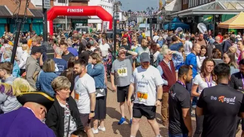 Hailsham News In the town centre of Hailsham near the finish line, hundreds of people gather in running gear and spectating