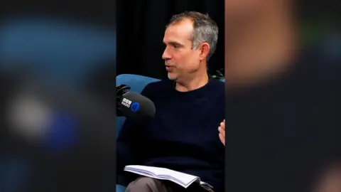 What's Up Docs podcast host Chris van Tulleken speaking into a Radio 4 mic in a studio