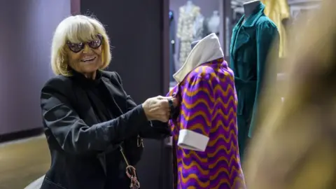 Fashion and Textile Museum Barbara Hulanicki adjusts clothes on display at the Fashion and Textile Museum