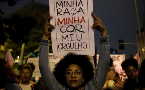 Reuters A demonstrator holds a sign during a protest by black women against racism and machismo, 25 July 2018