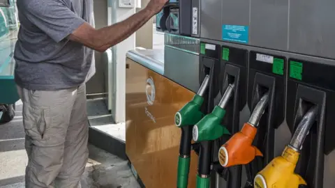 AFP Man selecting fuel pump at Total gas station for refueling his car