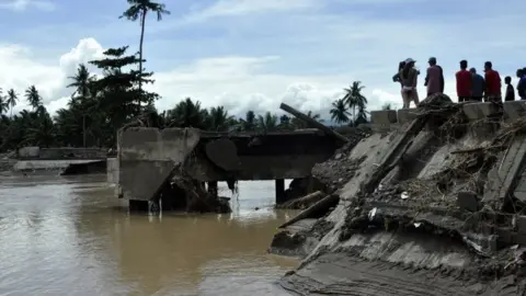 AFP/Getty Images People look at a collapsed bridge in Tubod, Mindanao island. Photo: 23 December 2017