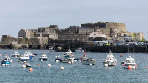 BBC Castle Cornet in the background and moored boats in the foreground on an overcast day