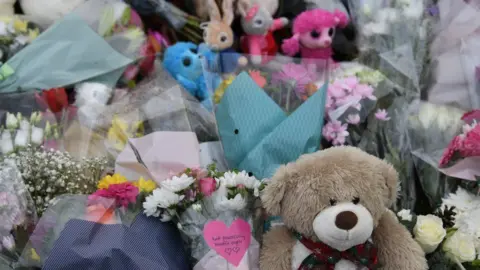 Joe Giddens A close-up of flowers and soft toys left in memory of two children who died in a house fire in Aynesbury, Cambridgeshire.