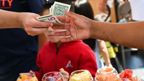 Getty Images a person pays for fruit in dollars