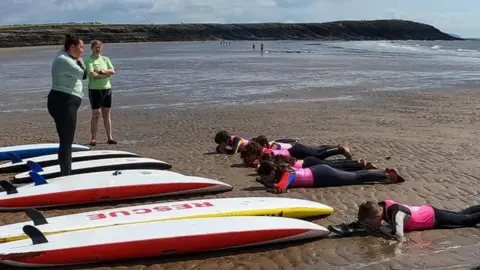 Rhondda Cold Knap Lifeguards children, trainers and surfboards on beach