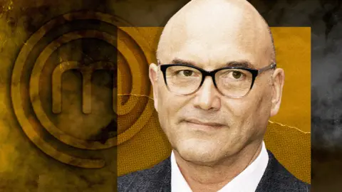A head and shoulders shot of Gregg Wallace, with a background featuring the MasterChef logo. The background is a mix of dark and golden hues, with the logo prominently displayed on the left side. Gregg Wallace is wearing a suit jacket over a white shirt.