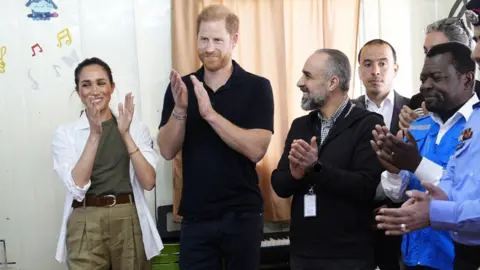 PA Media El duque y la duquesa de Sussex escuchan una clase de música durante una visita al Centro Juvenil QuestScope en el campo de refugiados de Za'atari.