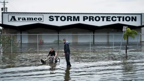 AFP Brad Matheney offers help to a man in a wheelchair in a flooded street in Galveston