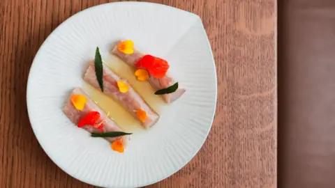 Will Barker A colourful plate of food on a brown wooden table.