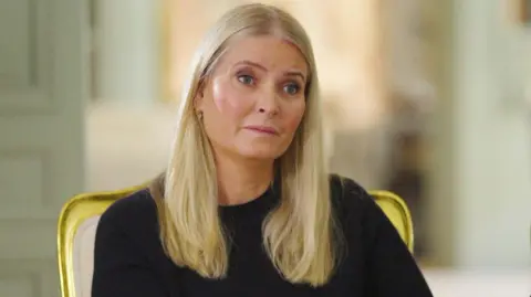 NRK A woman with blonde hair on the verge of tears in a black top