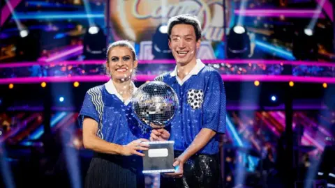 Karen Carney and Carlos Gu with their trophy after winning the 2025 series of Strictly Come Dancing.