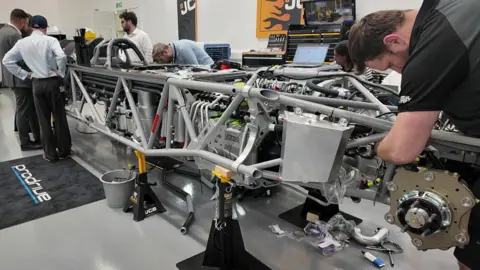A team of engineers work on the shell of the JCB Hydromax.