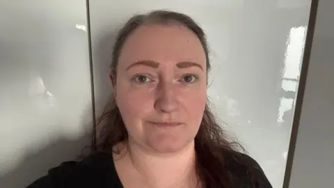 Jax Newman Headshot of a woman with brown hair against a plain white background. She has a slight smile but is looking quite serious.