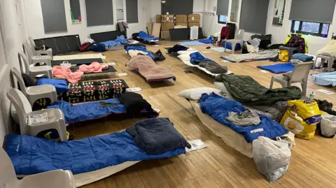 BBC Camp beds and sleeping bags are laid out in rows