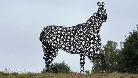 The whole of the horse sculpture against a blue sky