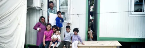 AFP An Afghan family with six children stand outside their container on 11 May 2017 at Malakassa refugee camp in Greece