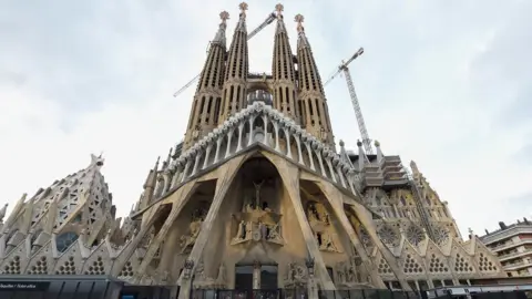 AFP Tourists walk by the "Sagrada Familia" basilica in Barcelona