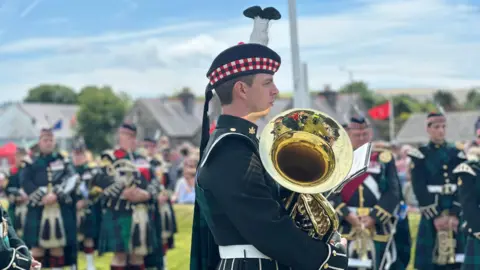 Close-up of a member of the band, who is in the green uniform.