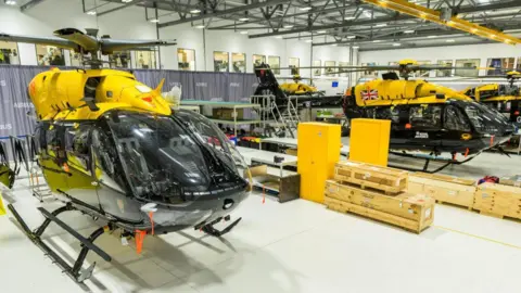 Several yellow airports lined up in a hangar.